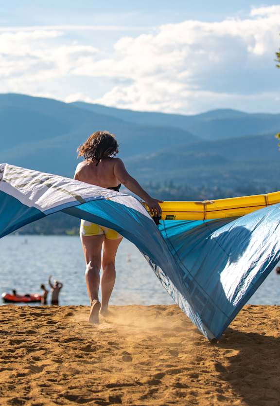 A woman is setting up a kite on a beach.