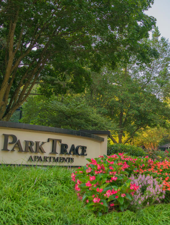 a sign for park trace apartments with flowers in front of it