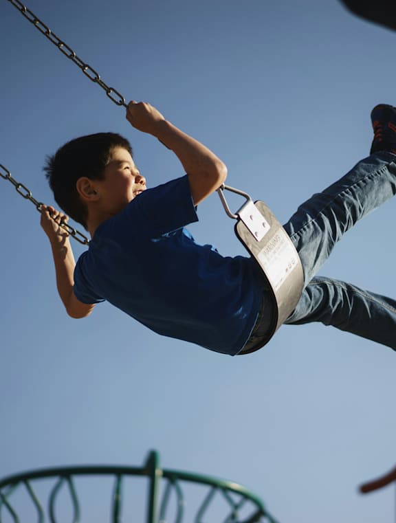 A boy is swinging on a swing set.