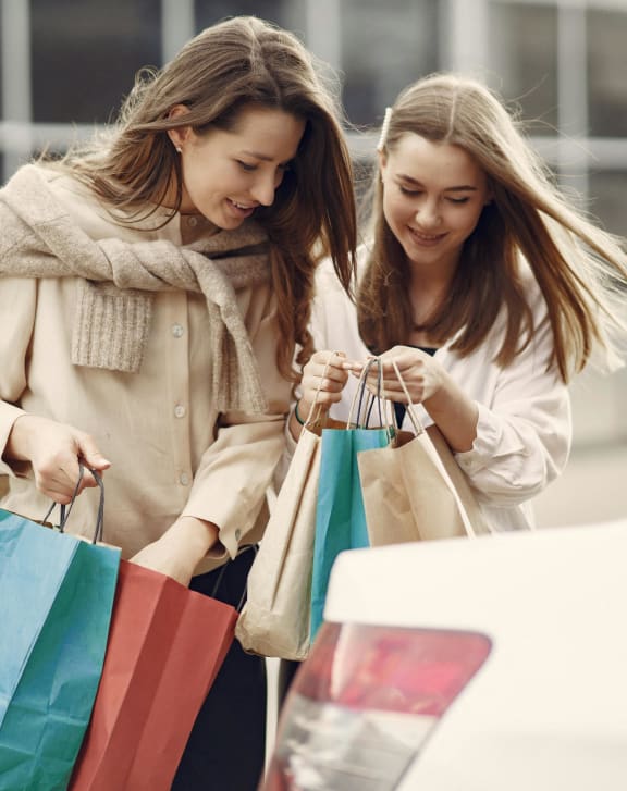 two women loading shopping bags into a car