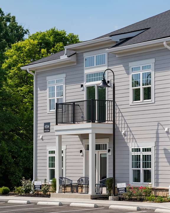 A grey two-story house with a balcony on the second floor.