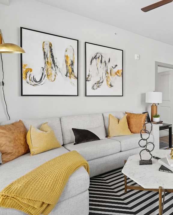 A living room with a grey sofa, a coffee table, and a ceiling fan.