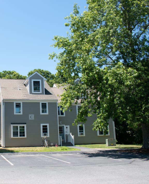 a large gray house with trees in a parking lot