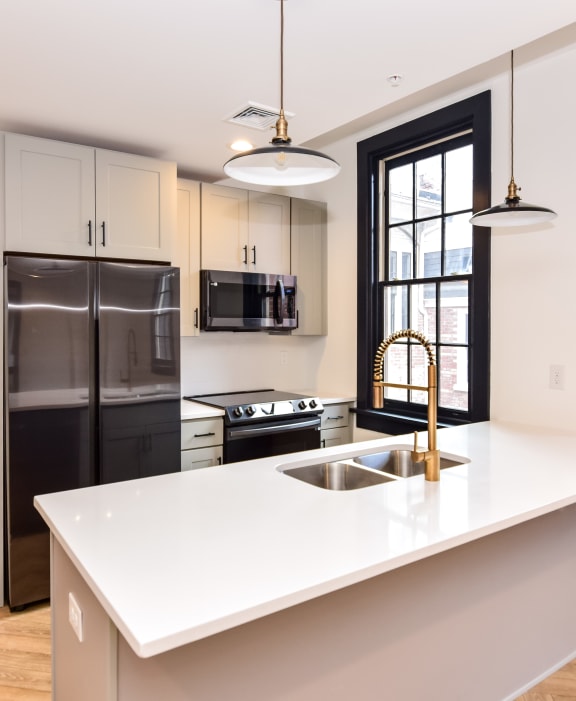 a kitchen with a white counter top and a black refrigerator