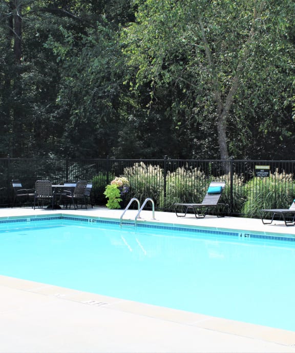 a swimming pool with black chairs and a fence around it at Hidden Creek, Georgia