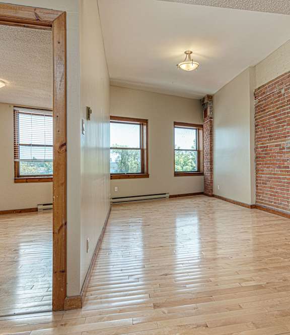 A room with wooden floors and a brick wall.