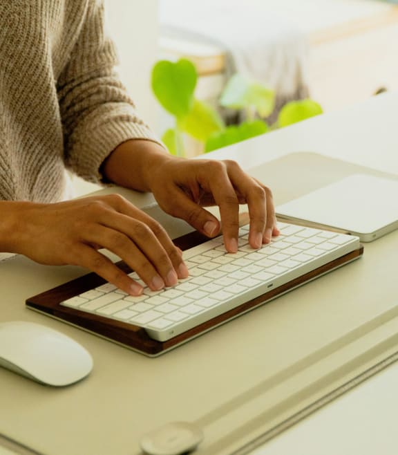a woman typing on a computer keyboard and mouse