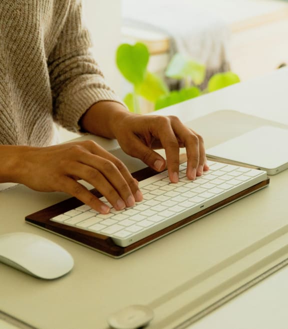 a woman typing on a computer keyboard and mouse