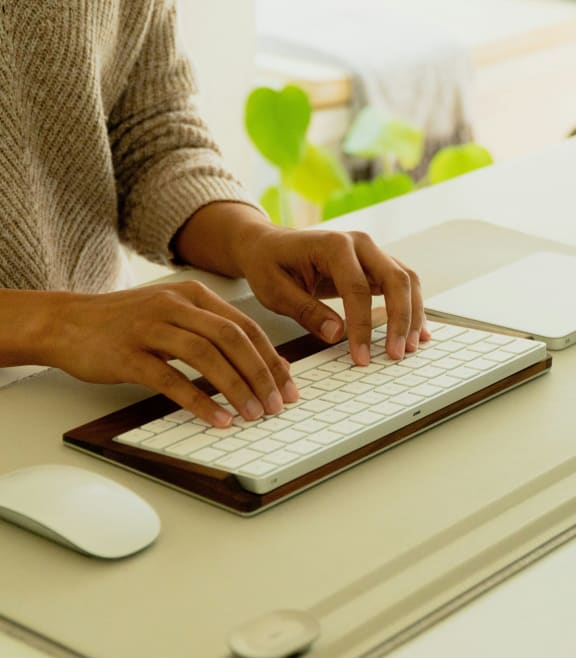 a woman typing on a computer keyboard and mouse