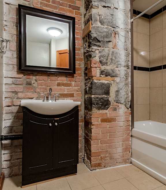 A bathroom with a stone wall and a white shower curtain.
