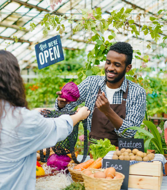 a man and woman selling produce at a farmers market at Willow Bend Apartments, Durham