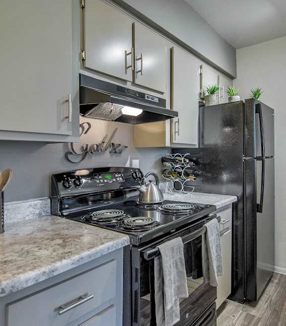 A kitchen with a black refrigerator and a white counter top.