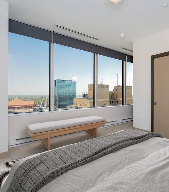 a bedroom with a bed and a closet with a city view