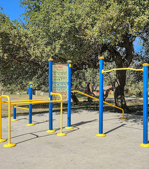 A blue and yellow outdoor gym equipment set up in a park.