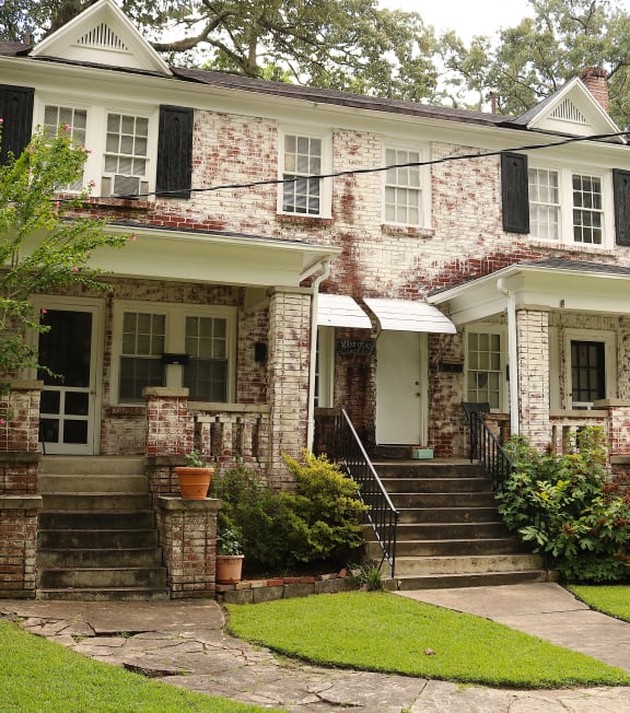 an old brick house with black shutters and a sidewalk