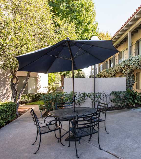 a patio with a table and umbrella in front of a building