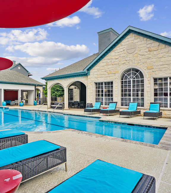 A large swimming pool with lounge chairs and a building in the background.