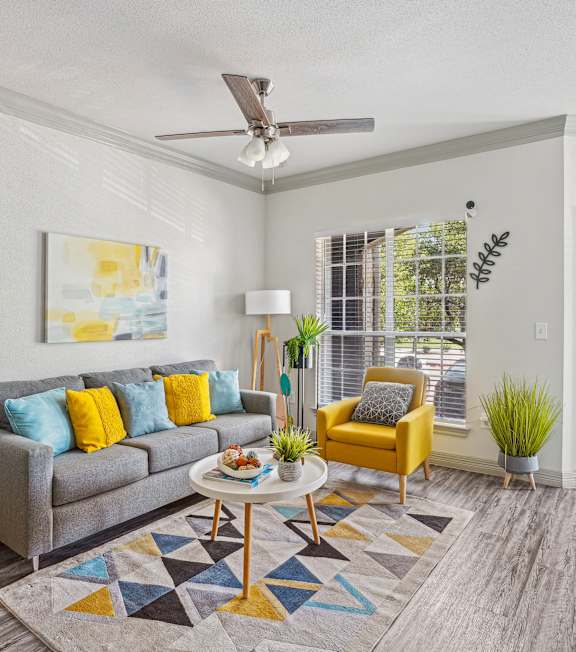 A living room with a grey couch, yellow chair, and a painting on the wall.