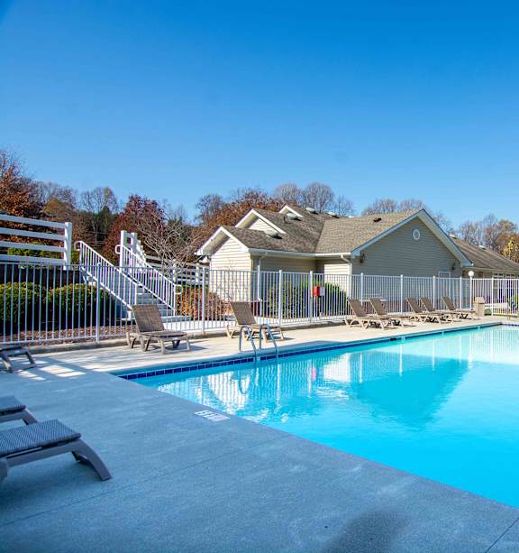A swimming pool surrounded by a fence and chairs.