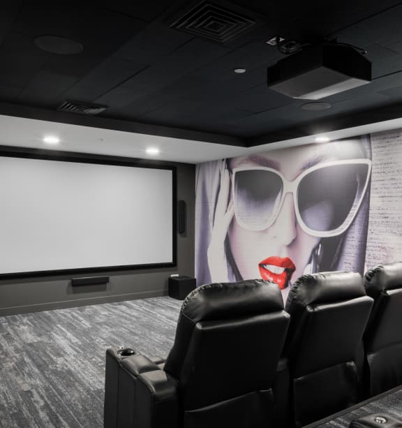 a large screening room with black leather chairs and a projector screen