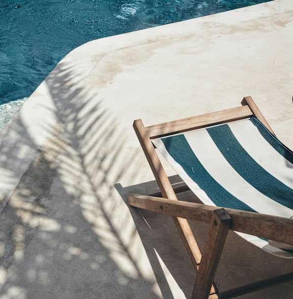 A pool with a metal ladder and a planter on the side.