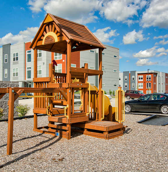 A wooden playhouse sits in the foreground of a residential area.