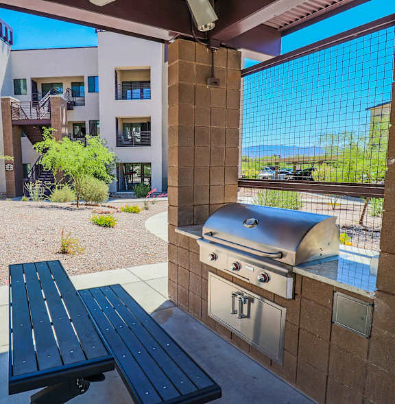 A BBQ grill is in the foreground of a residential area with palm trees.