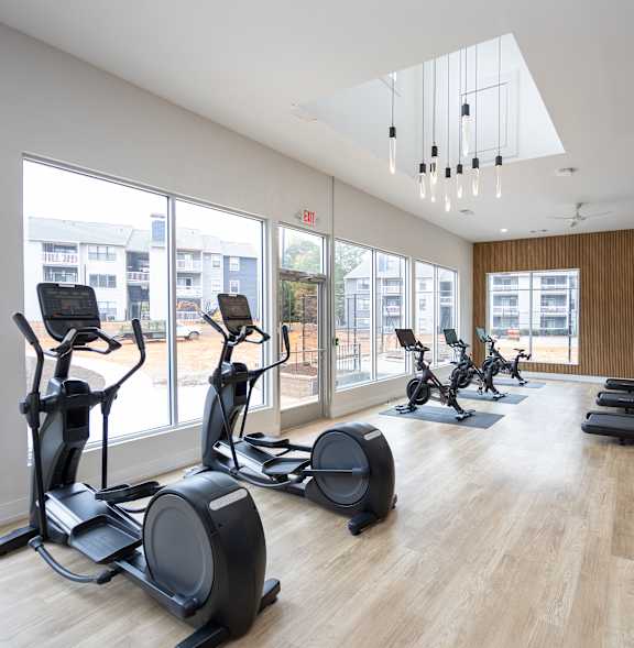 A gym with treadmills, exercise bikes and a wooden floor.