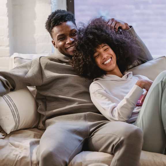A man and a woman are sitting on a couch, both wearing matching outfits.