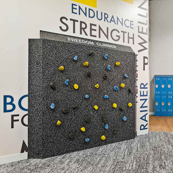 A climbing wall in a gym with a sign that says "Endurance Strength".