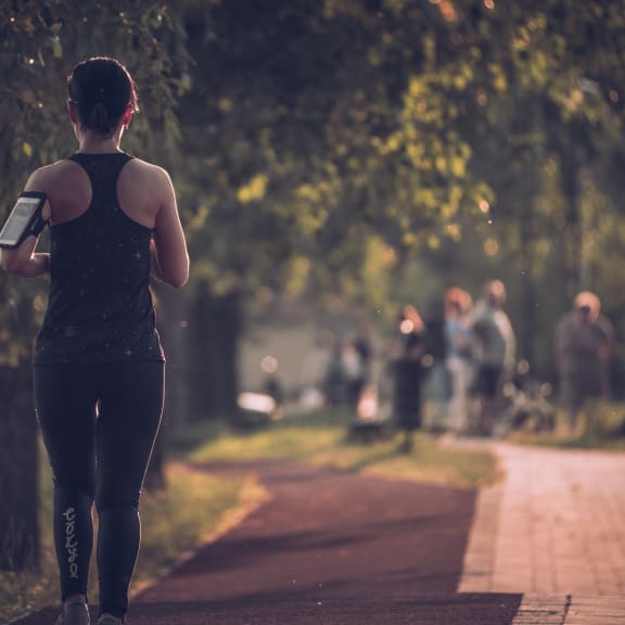 a woman running down a path with a water bottle in her hand