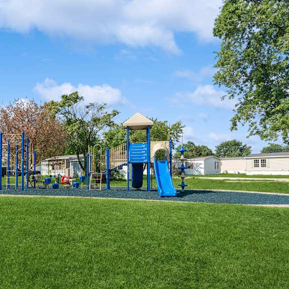 A playground with a blue umbrella and a green slide.