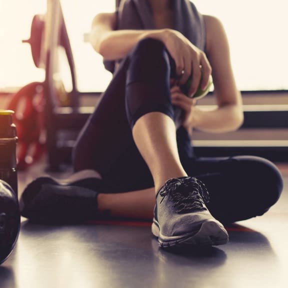 a woman sitting on the floor next to a dumbbell at Stone Creek at Old Farm Apartments, Texas