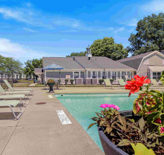 a pool with lounge chairs and a house in the background at Bay Pointe Apartments in IN 47909