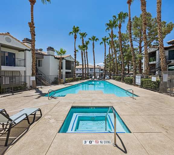 A pool surrounded by palm trees and lounge chairs.