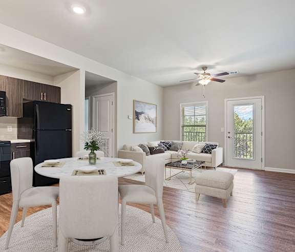 A modern dining room with a black fridge and stove, a white dining table with chairs, and a ceiling fan.