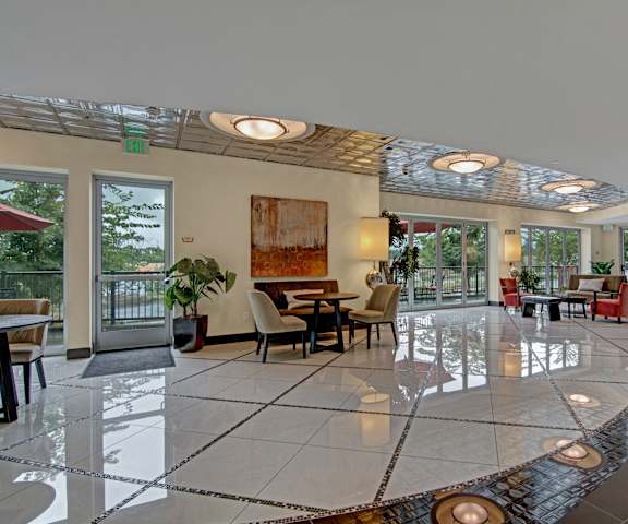 The lobby with various chairs and tables next to the large sliding glass doors to the patio with overhead lighting at the Artiste Apartment Homes.