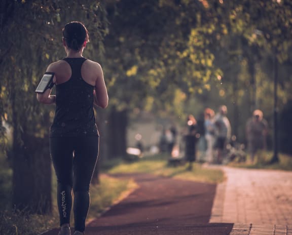 a woman running down a path with a water bottle in her hand