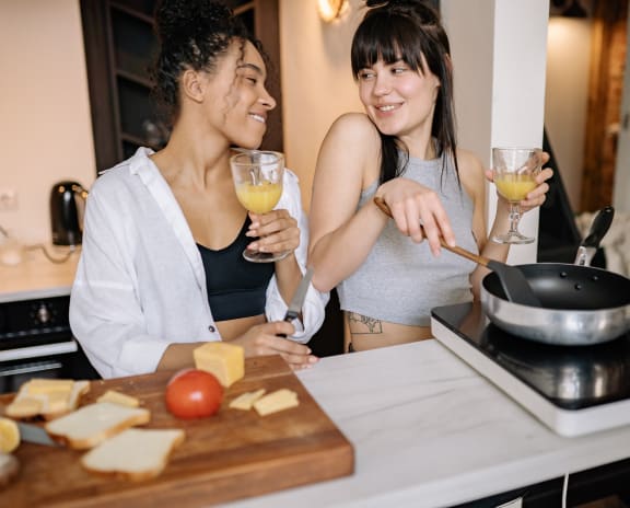 two women cooking and drinking wine in the kitchen