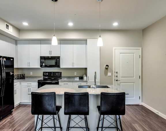 A kitchen with white cabinets and a black countertop.