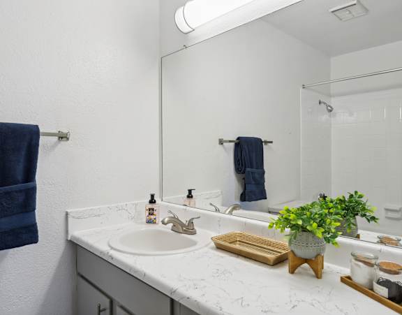 A bathroom with a white countertop and a blue towel hanging on the wall.