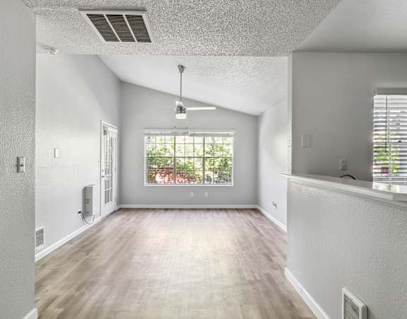 A spacious room with a window overlooking a garden.