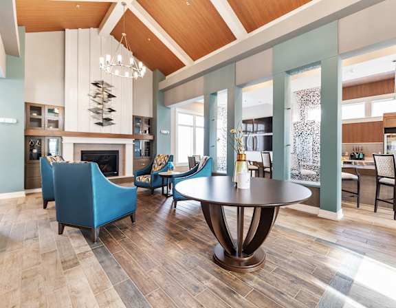 A modern kitchen with a granite countertop and black chairs.