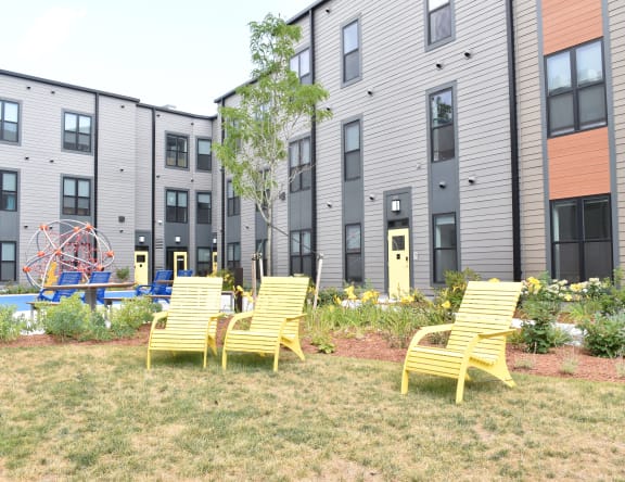 a group of yellow chairs in front of an apartment building