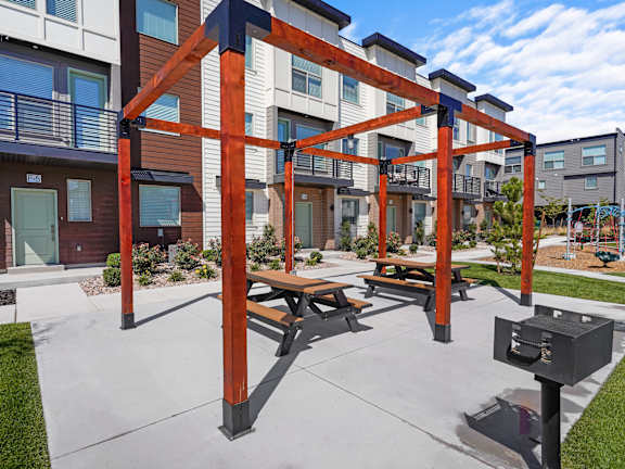 A playground with a swing set and picnic tables is located in a courtyard between apartment buildings.