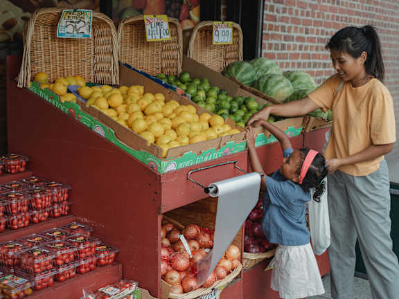 A woman and a child are shopping for fruit at a market.
