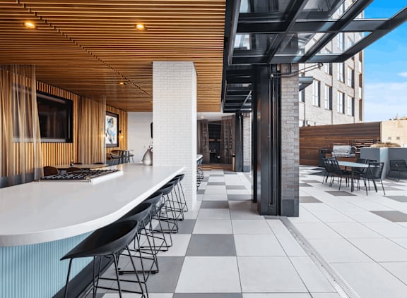 A modern bar area with black and white tiled floors and a long white counter.