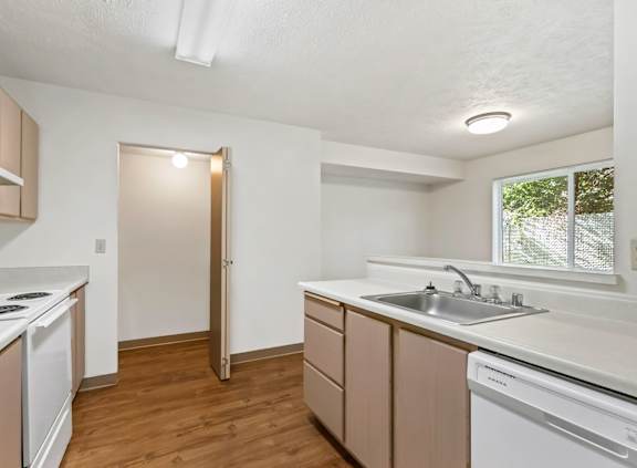 A kitchen with white appliances and wooden cabinets.
