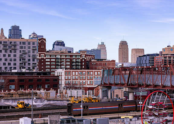 A train is on the tracks in front of a city skyline.