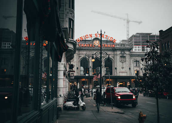 A city street with a red car and a construction crane in the background.